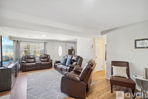 A living room with brown leather furniture and a large window.