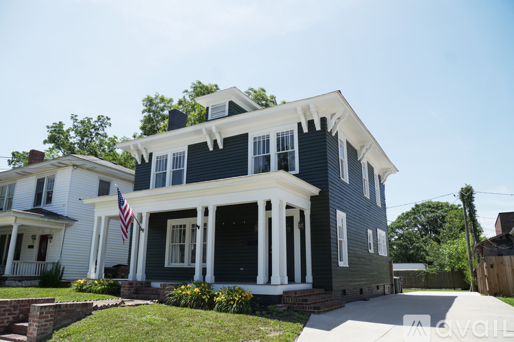 A blue house with white columns and an American flag on the front porch.