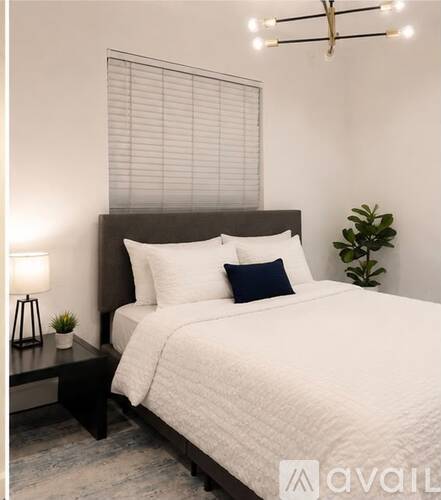 A bedroom with a large bed and a small plant on the side table.