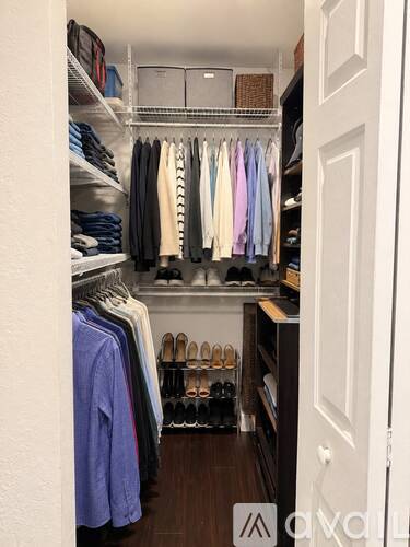 A white closet with clothes and shoes.