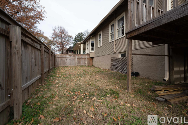 A backyard with a wooden fence and a house in the background.