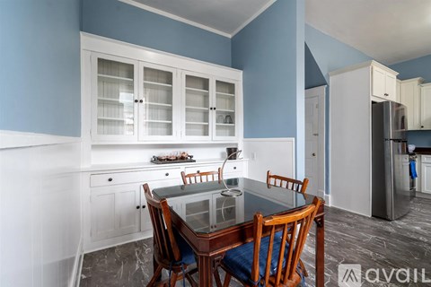 A kitchen with a table and chairs in the foreground and a refrigerator in the background.