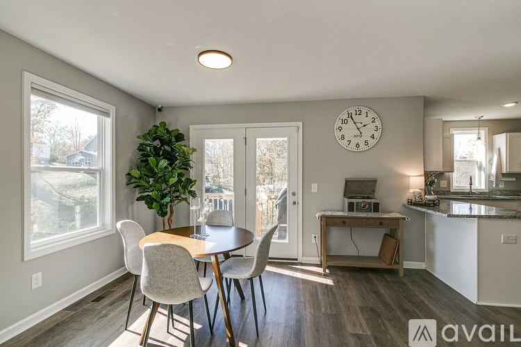 A dining room with a table and chairs and a clock on the wall.