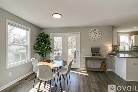 A dining room with a table and chairs and a clock on the wall.