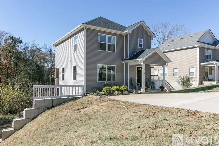 A two-story house with a grey exterior and a white picket fence.