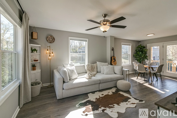 A living room with a white couch and a guitar hanging on the wall.