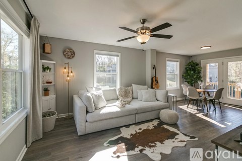 A living room with a white couch and a guitar hanging on the wall.