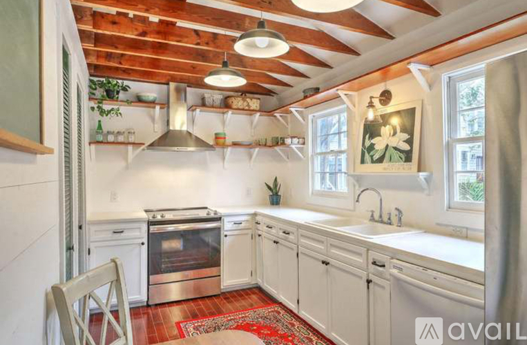 A kitchen with white cabinets and a wooden ceiling.