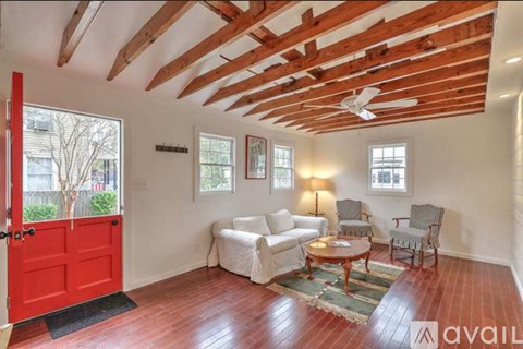 A room with a red door and wooden beams on the ceiling.