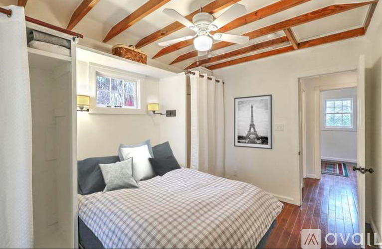 A bedroom with a bed, a ceiling fan, and a picture of the Eiffel Tower on the wall.