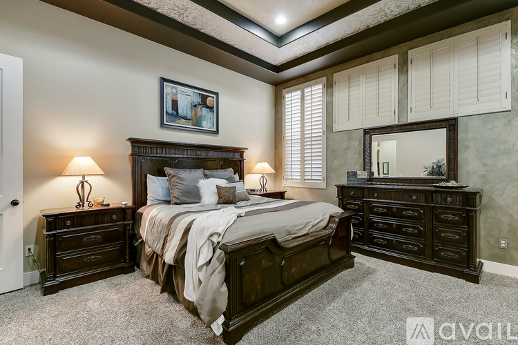 A bedroom with a large bed, a dresser, and a nightstand with a lamp.