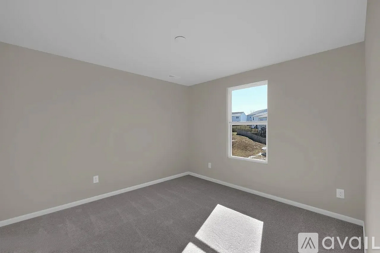 A room with a window showing a view of a fence and trees.