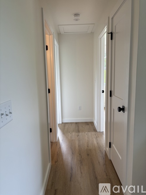 A hallway with a white door and a light switch on the wall.