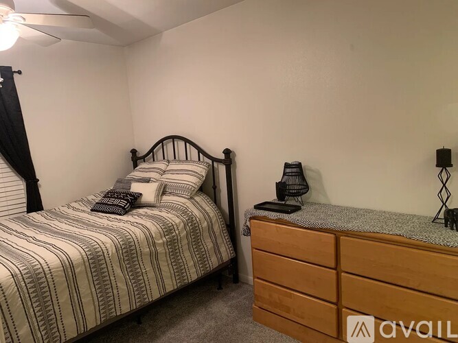 A bedroom with a bed and a nightstand with a lamp on it.