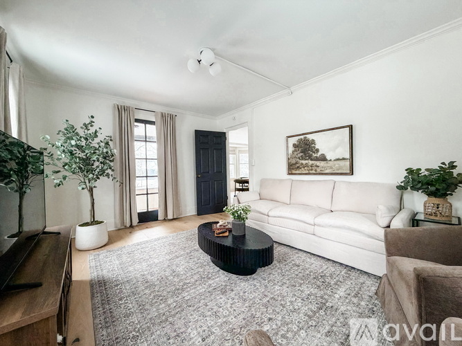 A living room with a white couch, a coffee table, and a painting on the wall.