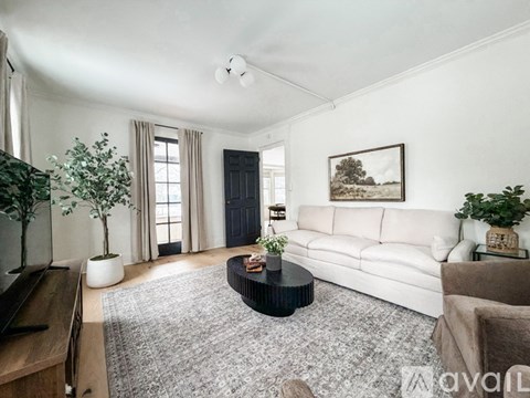 A living room with a white couch, a coffee table, and a painting on the wall.