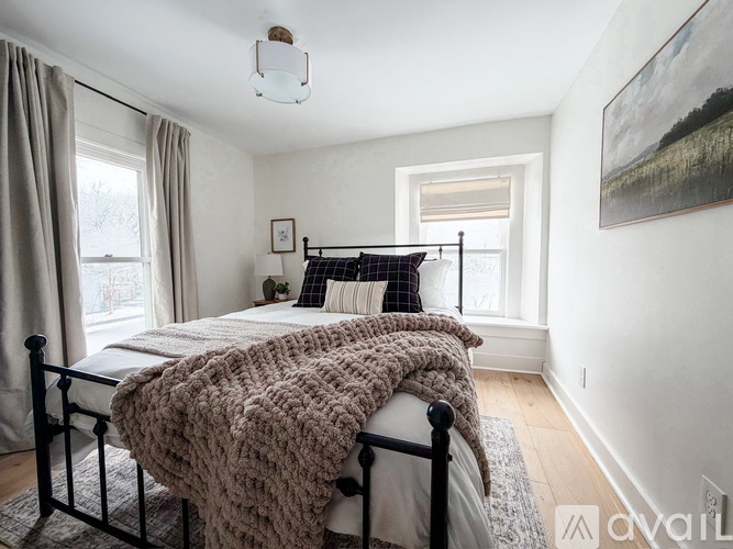 A bedroom with a bed covered in a brown blanket.
