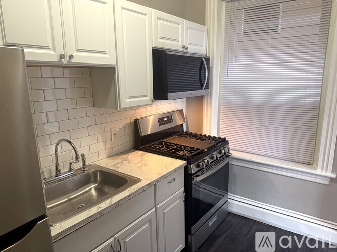 A kitchen with a stove, sink, and cabinets.