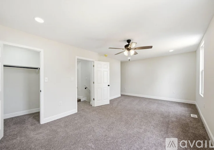 A spacious room with a ceiling fan and carpeted floor.