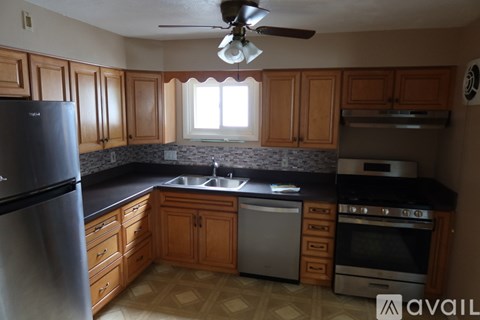 A kitchen with wooden cabinets and a stainless steel refrigerator.