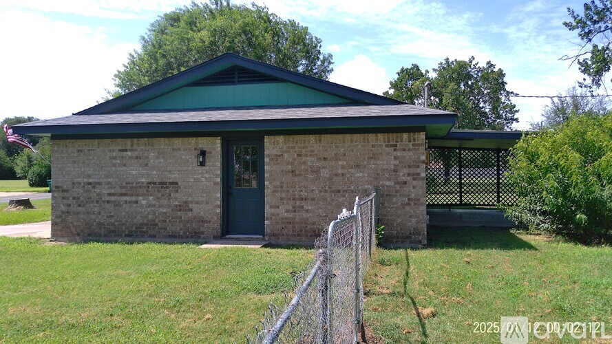 A small building with a green roof and a fence in front.