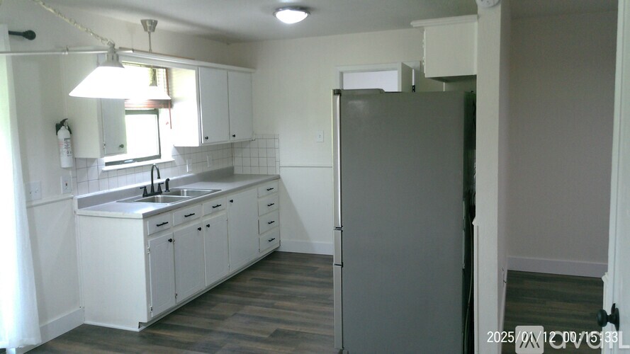 A kitchen with white cabinets and a grey fridge.