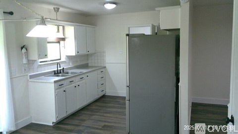 A kitchen with white cabinets and a grey fridge.