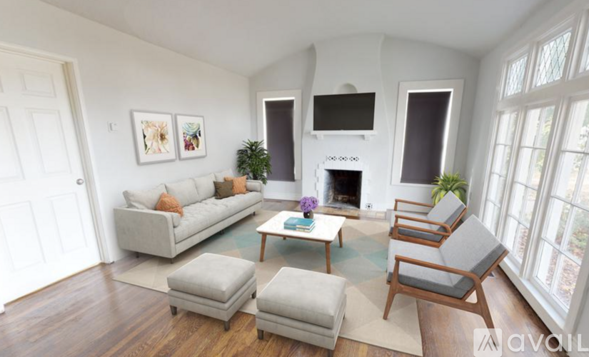 A living room with a grey couch, a white fireplace, and a wooden floor.