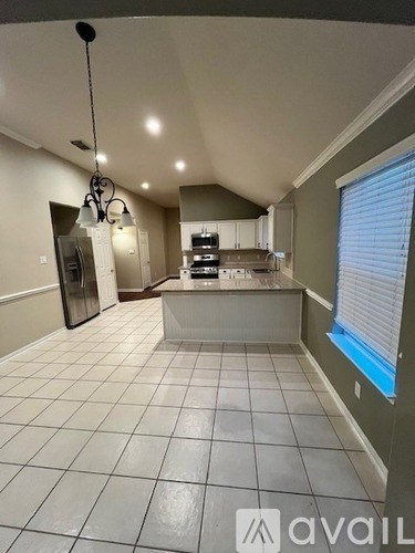 A kitchen with white tiled floors and a hanging light fixture.