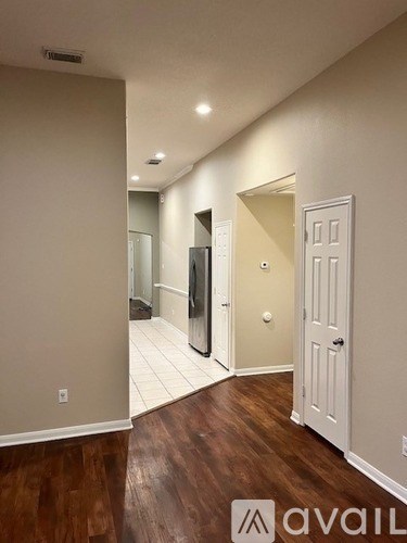 A hallway with a door on the right and a mirror on the wall.