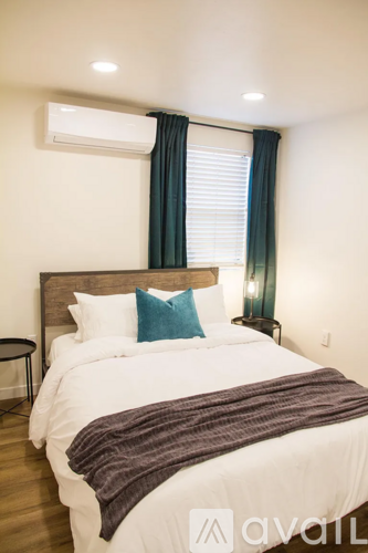A bedroom with a large bed and a window with curtains.