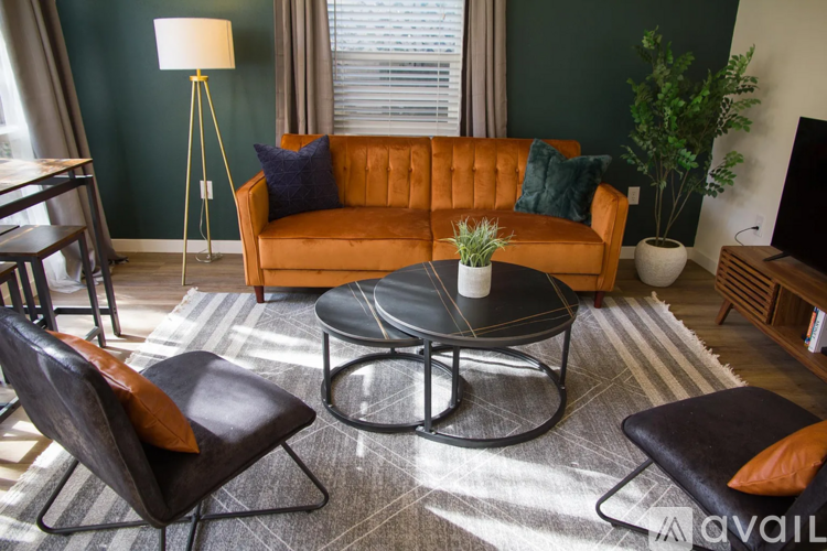 A living room with a brown sofa, a black coffee table, and a grey rug.