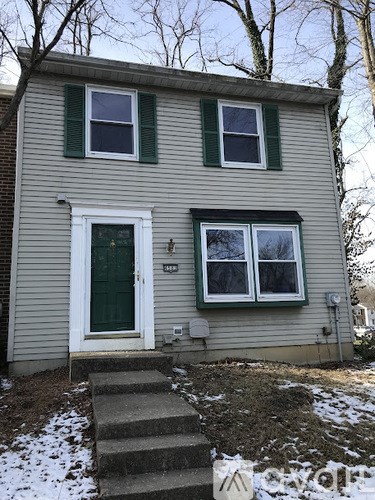 A house with a green door and two windows with green shutters.