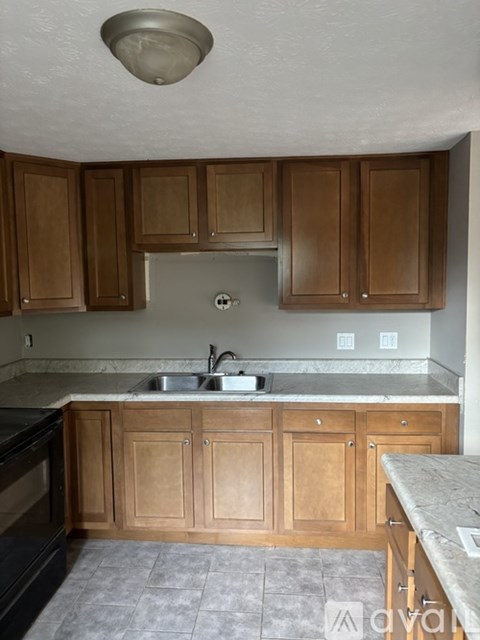 A kitchen with wooden cabinets and a marble countertop.