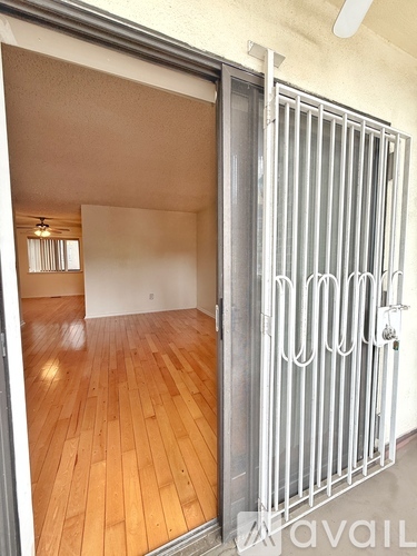 A room with wooden floors and a white door with bars.