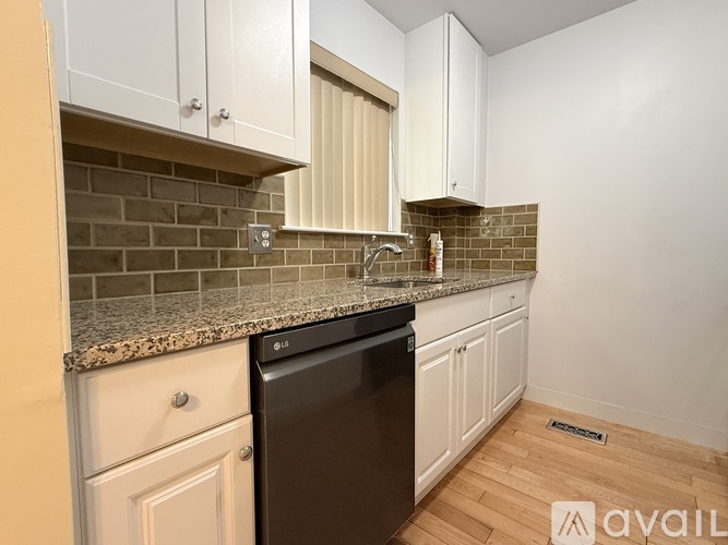 A kitchen with a black dishwasher and white cabinets.