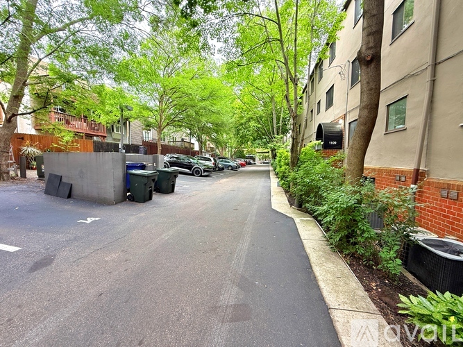A tree-lined street with a sidewalk and apartment buildings.