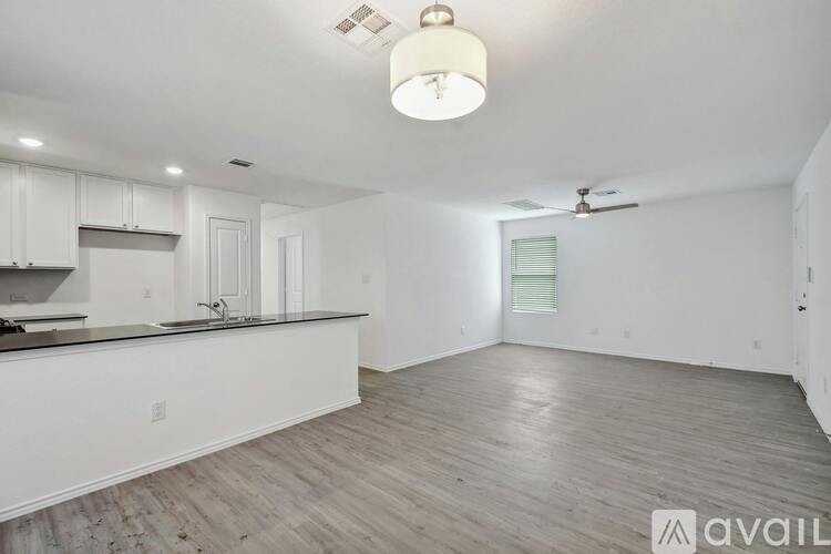 A spacious kitchen with white cabinets and a wooden floor.