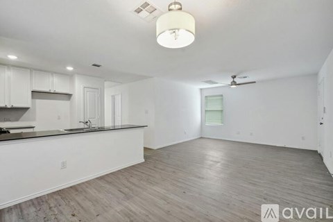 A spacious kitchen with white cabinets and a wooden floor.