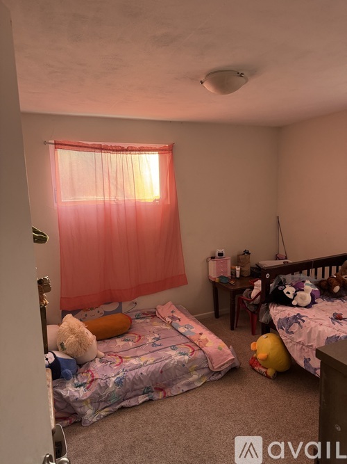 A bedroom with two beds and a teddy bear on the floor.