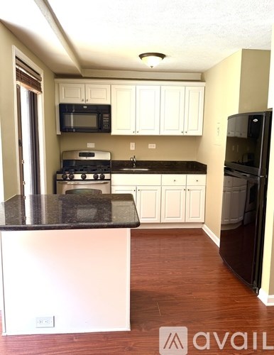 A kitchen with white cabinets and a black countertop.
