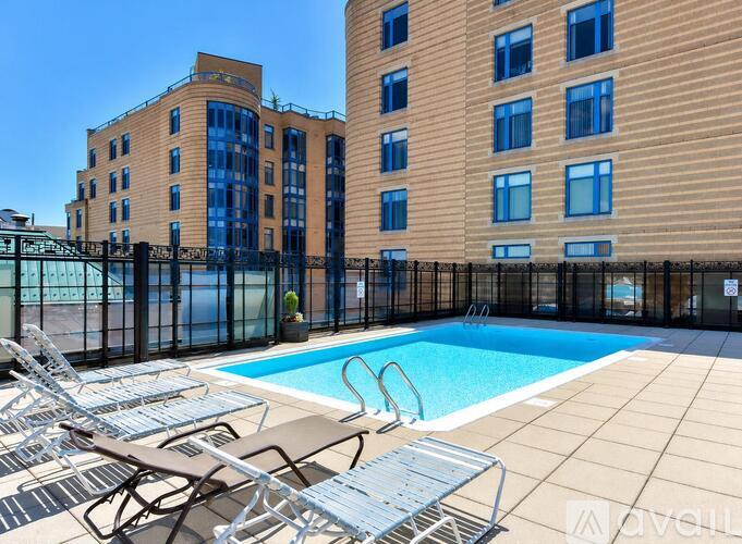 A pool area with chairs and a building in the background.