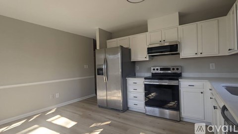 A kitchen with white cabinets and stainless steel appliances is available for rent.