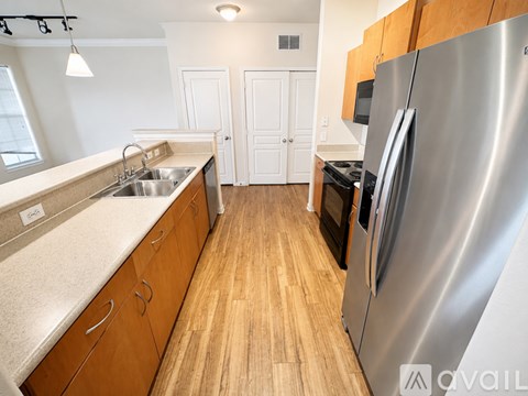 A kitchen with a stainless steel refrigerator and wooden cabinets.