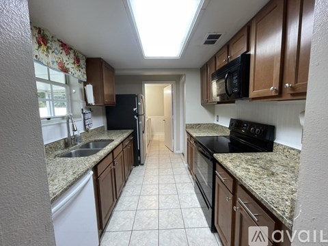 A kitchen with brown cabinets and a black refrigerator.
