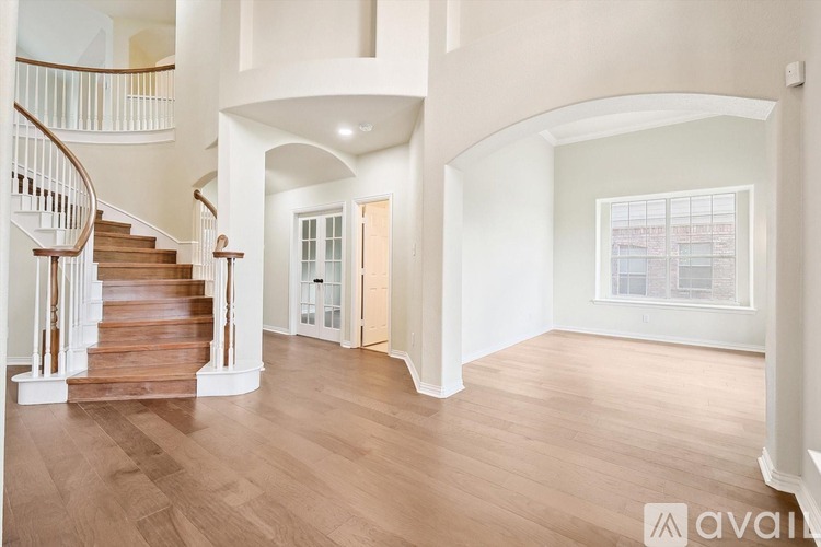A spacious room with wooden floors and a large window.