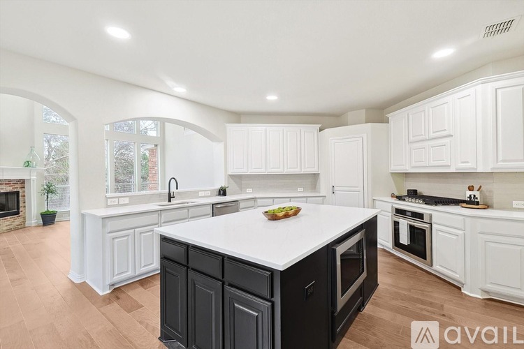 A modern kitchen with white cabinets and a black island.