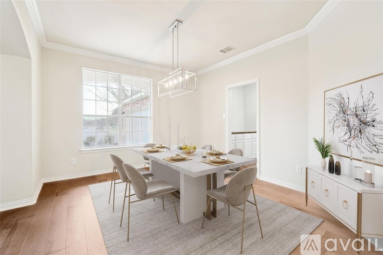 A dining room with a table set for four and a chandelier hanging from the ceiling.