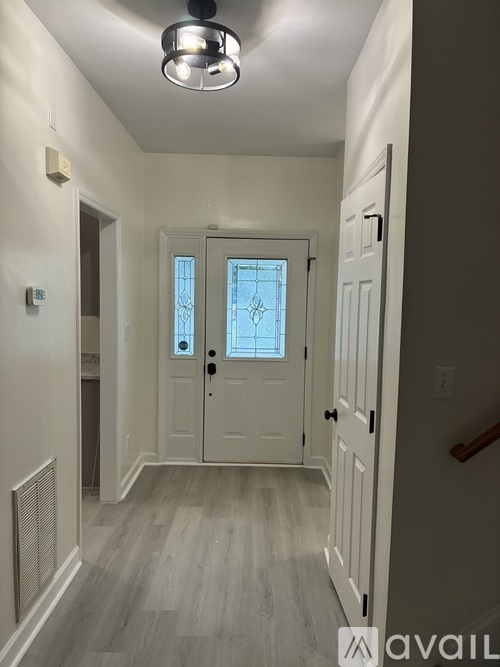 A hallway with a white door and a window.