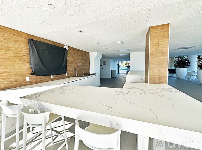 A modern kitchen with a long white table and chairs.